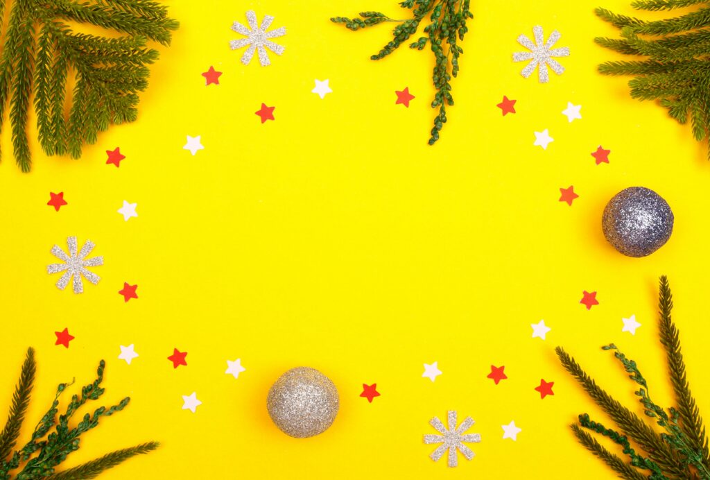 Bright Christmas decorations on yellow background with copy space for text.